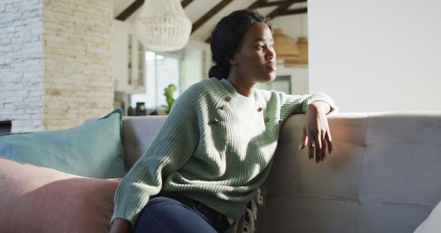 Image of thoughtful african american woman sitting on sofa and looking outside window - Download Free Stock Photos Pikwizard.com