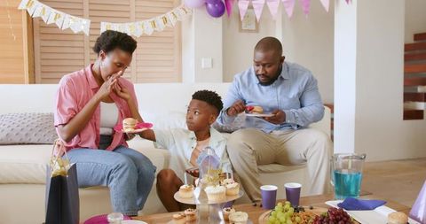 African American Family Celebrating Birthday at Home Sharing Cupcakes on Sofa