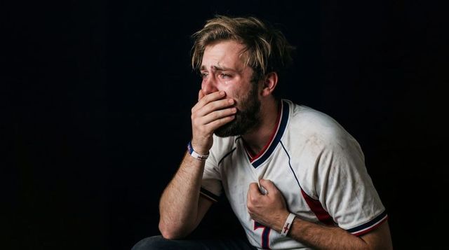 Crying sports fan clutching chest and covering mouth dramatic portrait with wristbands
