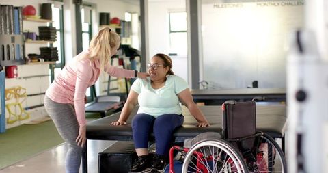 Therapist assisting patient transferring from wheelchair during rehabilitation session