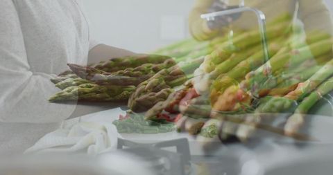 Asparagus bundle overlapping couple prepping fresh greens in modern home kitchen
