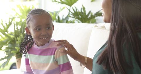 African american mother connecting with daughter on living room couch, cozy natural light