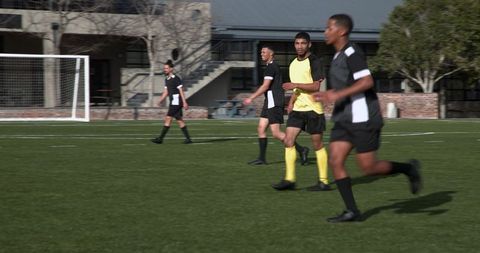 Soccer Players Competing Intensely on Field Near School