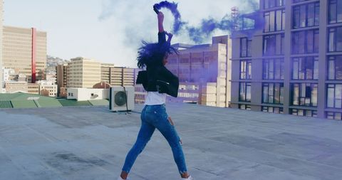Joyful Urban Celebration with Woman Waving Blue Smoke Flare on Rooftop