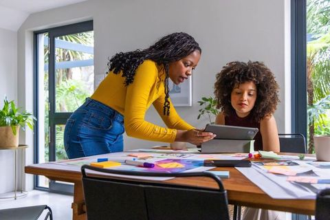 African american women collaborating in home studio reviewing tablet and design notes