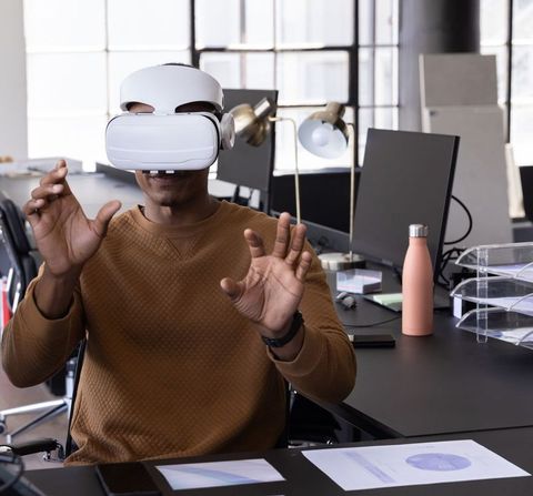 African american man experiencing virtual reality while working at modern office desk
