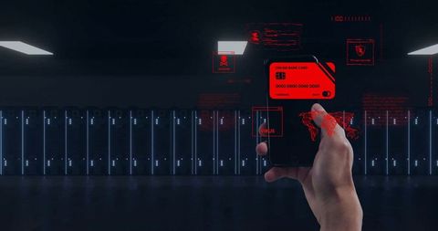 Hand holding smartphone showing holographic red cyber threat alerts in dark data center