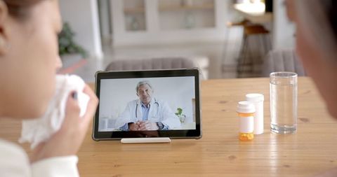 Woman Consulting Doctor Online Through Tablet at Home