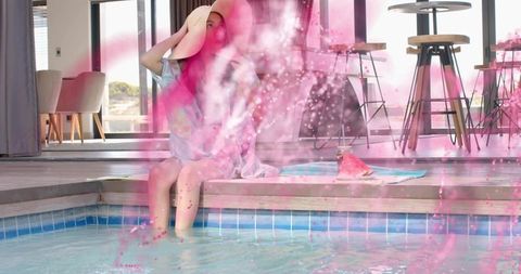 Relaxing poolside moment: woman in floppy hat soaking toes amid pink smoke and towel