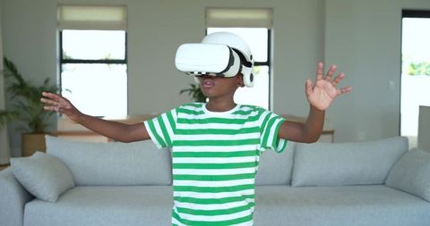 Boy Exploring Virtual World Wearing VR Headset and Reaching Forward in Living Room