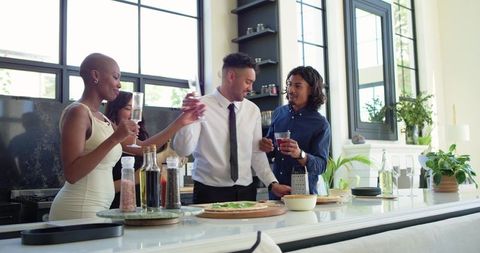 African american friends toasting while grating cheese and making pizza in modern kitchen