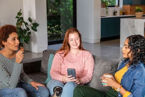 Diverse Female Friends Relaxing with Smartphone in Modern Living Room