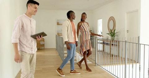 Happy couple viewing modern home with estate agent