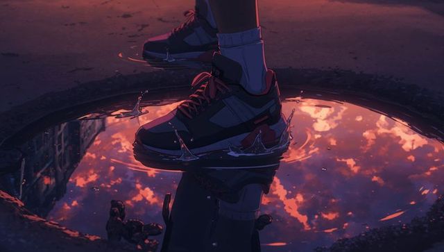 Red-accented sneakers splashing sunset puddle reflecting fiery sky at dusk