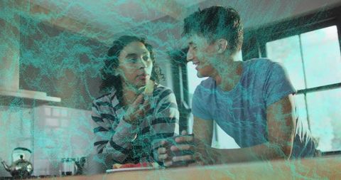 Sunlit kitchen conversation between young adults sharing coffee and casual morning laughs