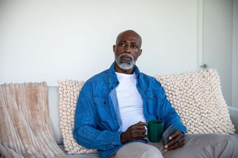 Senior Man Relaxing with Coffee and Smartphone in Cozy Living Area