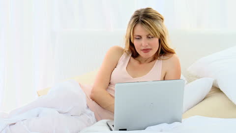 Relaxed Woman Using Laptop in Comfortable Bedroom Setting
