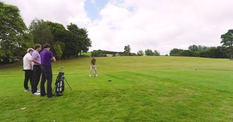 Male golfers preparing shot on verdant golf course