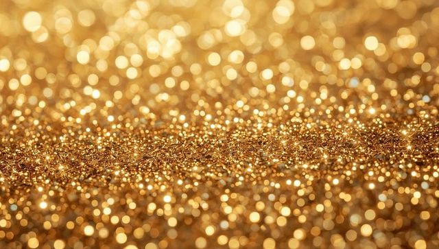 Shimmering gold glitter bokeh with sparkling metallic flakes and warm amber macro glow