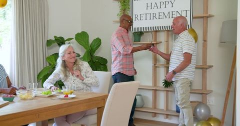 Senior friends celebrating retirement with banner and balloons