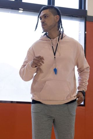 Mid-adult coach in gym wearing pink hoodie with focused expression