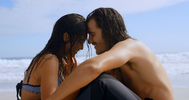 Romantic couple embracing on sandy beach near ocean on a sunny day. They seem deeply in love and are enjoying a vacation. Ideal for marketing romantic getaways, travel blogs, summer advertisements, or relationship counseling websites.