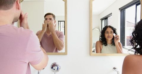 Diverse couple practicing skincare routine together in bright bathroom