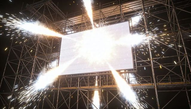 Central led screen erupting golden sparks on outdoor night stage scaffolding and catwalks