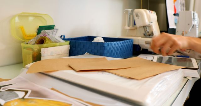 A person works on a sewing project at home. Various sewing supplies and a sewing machine indicate a crafting or tailoring activity.