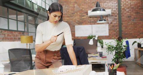 Architectural Designer Examining Scale Model in Open Office Studio