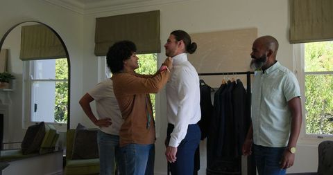 Friends supporting groom with wedding preparations