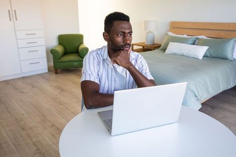 Man Contemplating While Working in Stylish Bedroom Office