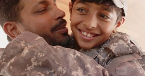 Father and son in camouflage hugging with joyful bond