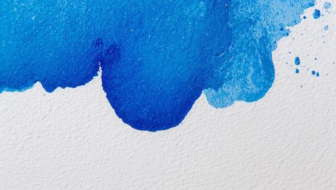 Flowing blue watercolor wash on textured paper showing granulation, drips and splatters