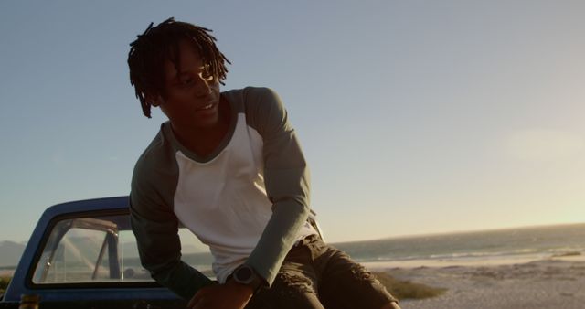 Young man enjoying sunset at the beach, leaning on truck - Download Free Stock Images Pikwizard.com