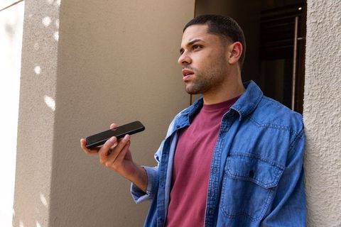 Man in casual attire speaking into smartphone outdoors