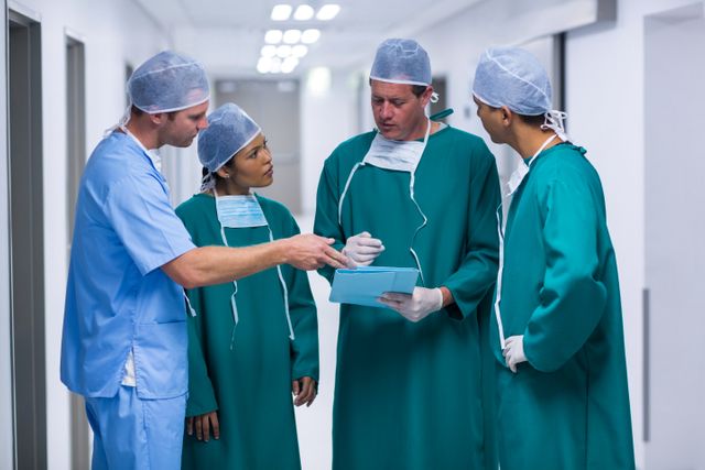 Surgeons and nurse having discussion on file in corridor of hospital