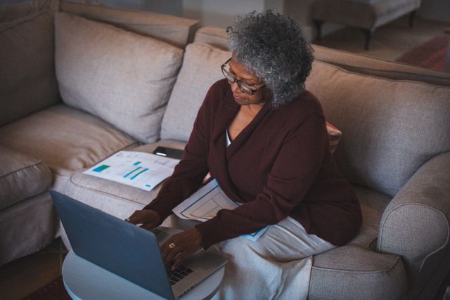 African american senior woman sitting on couch working using laptop - Download Free Stock Photos Pikwizard.com