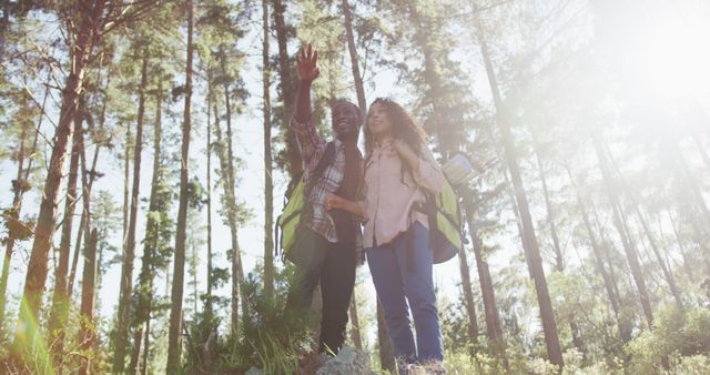 Smiling diverse couple looking away and hiking in countryside. healthy, active lifestyle and outdoor leisure time.