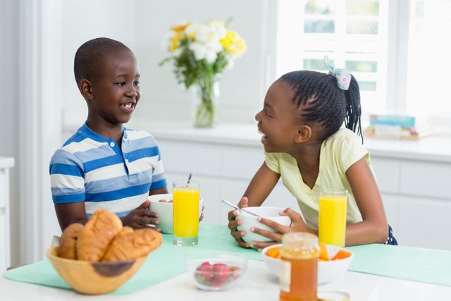 Siblings interacting while having breakfast on dining table at home