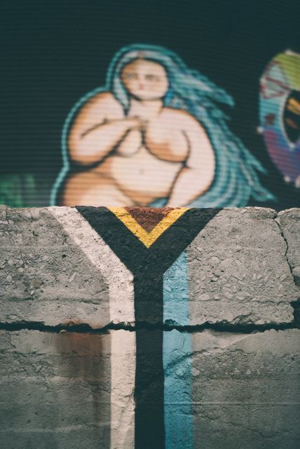 This image displays vibrant graffiti on a concrete wall, featuring a colorfully painted figure. It can be used in articles about urban art, street culture, or modern art exhibitions. It is also suitable for projects highlighting urban environments or artistic landscapes within cities.