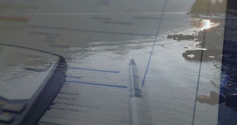 Double exposure ballpoint pen on lined document with calculator over tranquil rocky coastline
