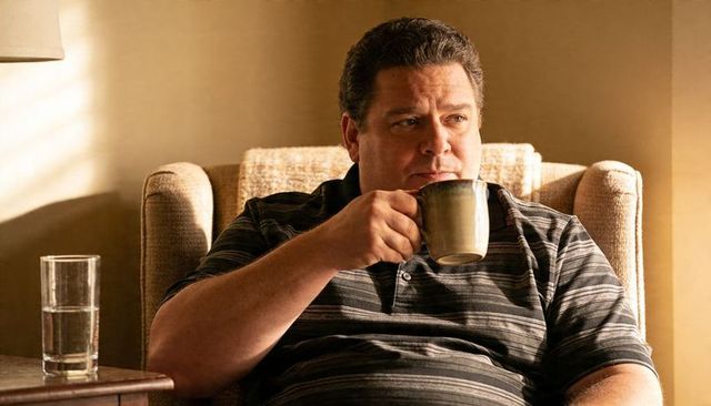 Contemplative middle-aged man sipping coffee in cozy armchair with warm morning light