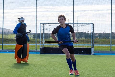 Young male field hockey players in action on turf field