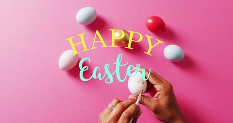 Celebrating easter: woman painting colorful eggs on pink background
