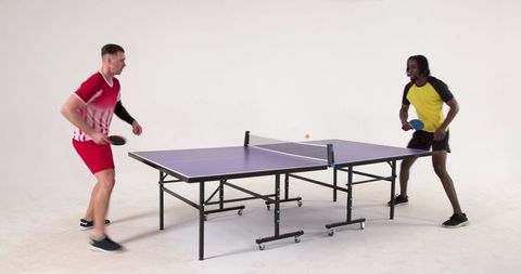 Diverse male athletes competing in ping pong game