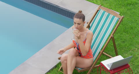 Woman Relaxing by Poolside in Summer with Glass of Wine