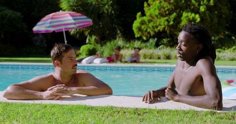 Two men relaxing at outdoor poolside in sunlit backyard