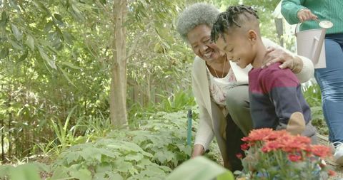 Multigenerational Family Gardening, Grandmother Teaching Grandson to Plant and Water Flowers