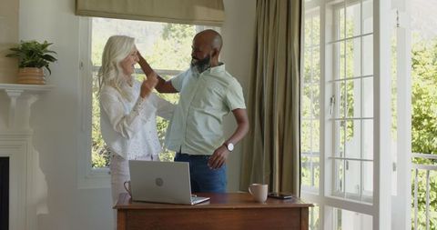 Joyful Couple Embracing at Home by Laptop